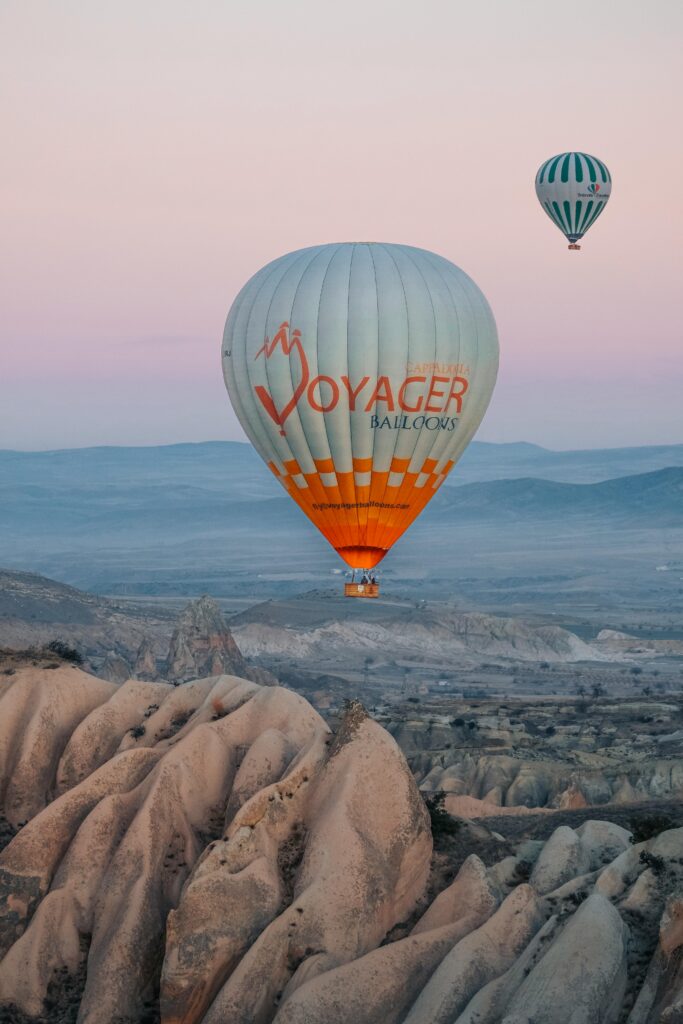 Scenic view of hot air balloons soaring over the unique rock formations of Cappadocia, Turkey at sunrise.