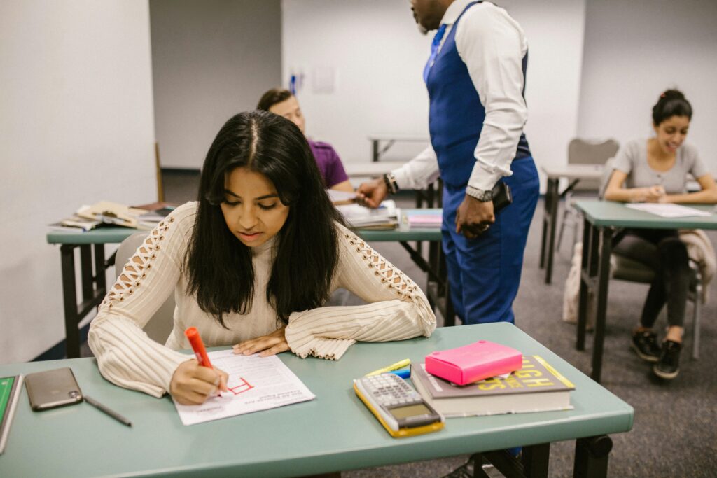 Students in a classroom during examination discussing and writing notes.